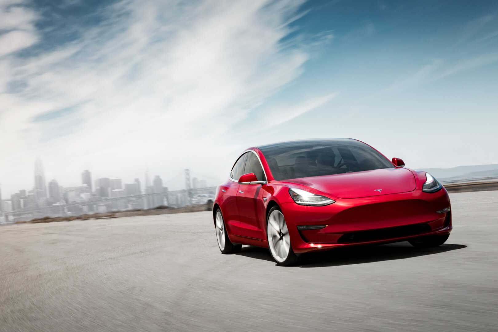 Roter Tesla Model 3 fährt auf der Straße