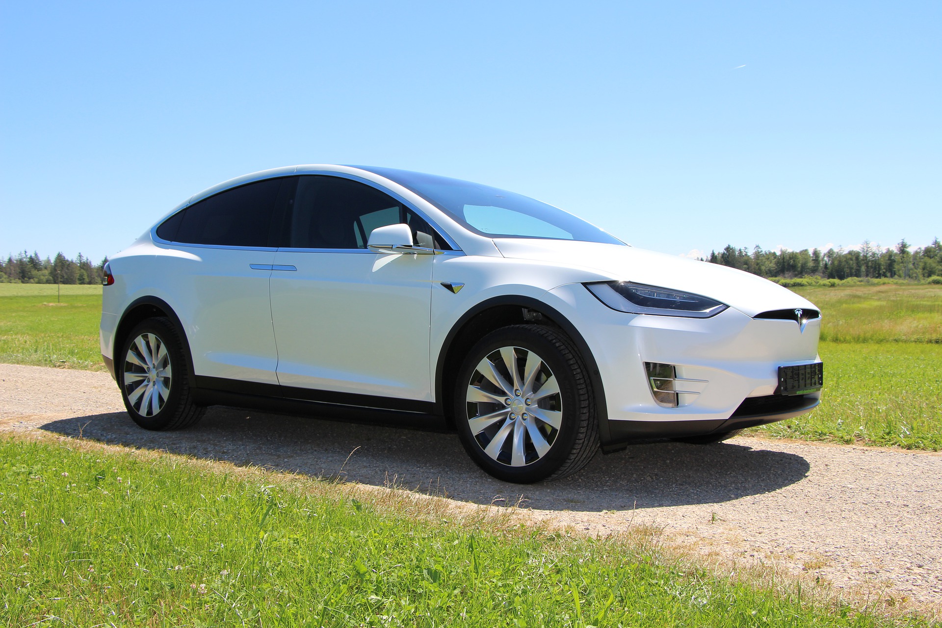 Weißes Tesla Elektroauto fährt auf einer Landstraße.