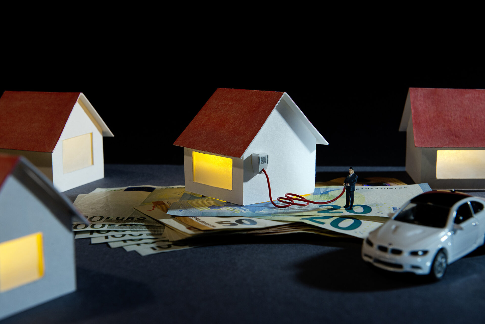 Miniaturdorf mit einem Elektroauto und Geldscheinen. Symbolbild: Wallbox-Förderung.